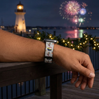Festive cruise-pattern watchband beside an illuminated harbor lighthouse