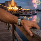 Film-strip watchband beside a glowing waterfront theater