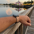 Orange checkerboard watchband beside a glowing waterfront carousel