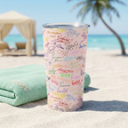Pink Autographs tumbler beside a mint towel on a tropical beach
