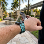 Teal icon-pattern watchband along a resort garden path