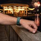 Watchband beside a glowing waterfront carousel and fireworks